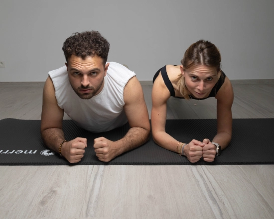 Man and woman performing a plank in Pilates, a mixed exercise to strengthen the body and enhance performance.