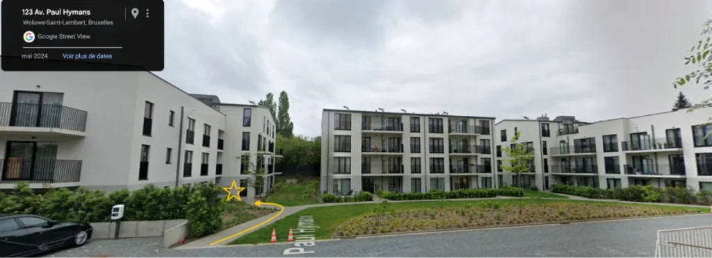 Bâtiment avec entrée du studio Reinforce Pilates à Woluwe, Bruxelles, indiqué par une flèche pour aider les visiteurs à trouver facilement l’accès.